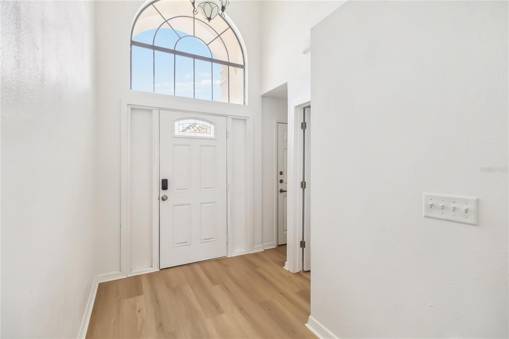 An entryway features light wood-look flooring, a white front door, and a tall arched window — 729 DOWNING CIRCLE, DAVENPORT, FL