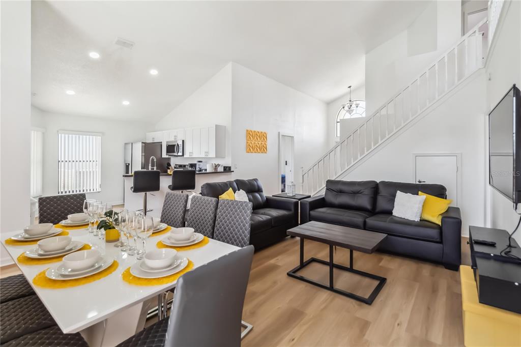 An open-concept living and dining area features white walls, light wood flooring, and a staircase — 729 DOWNING CIRCLE, DAVENPORT, FL