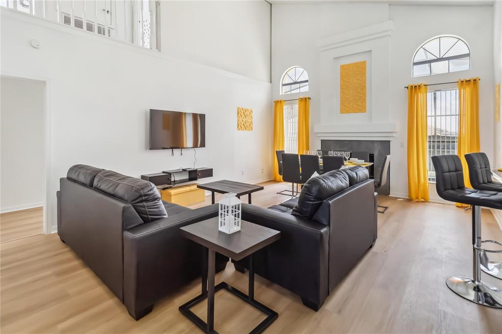 A living room with black leather sofas, a television, and a dining area with yellow curtains — 729 DOWNING CIRCLE, DAVENPORT, FL