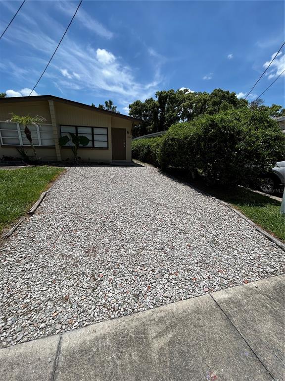 A gravel driveway leads to the front entrance of a single-story house with tan siding — 1720 MILLER AVENUE, WINTER PARK, FL