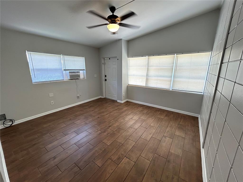 An empty room features wood-look tile flooring, a ceiling fan, and windows with blinds — 1720 MILLER AVENUE, WINTER PARK, FL