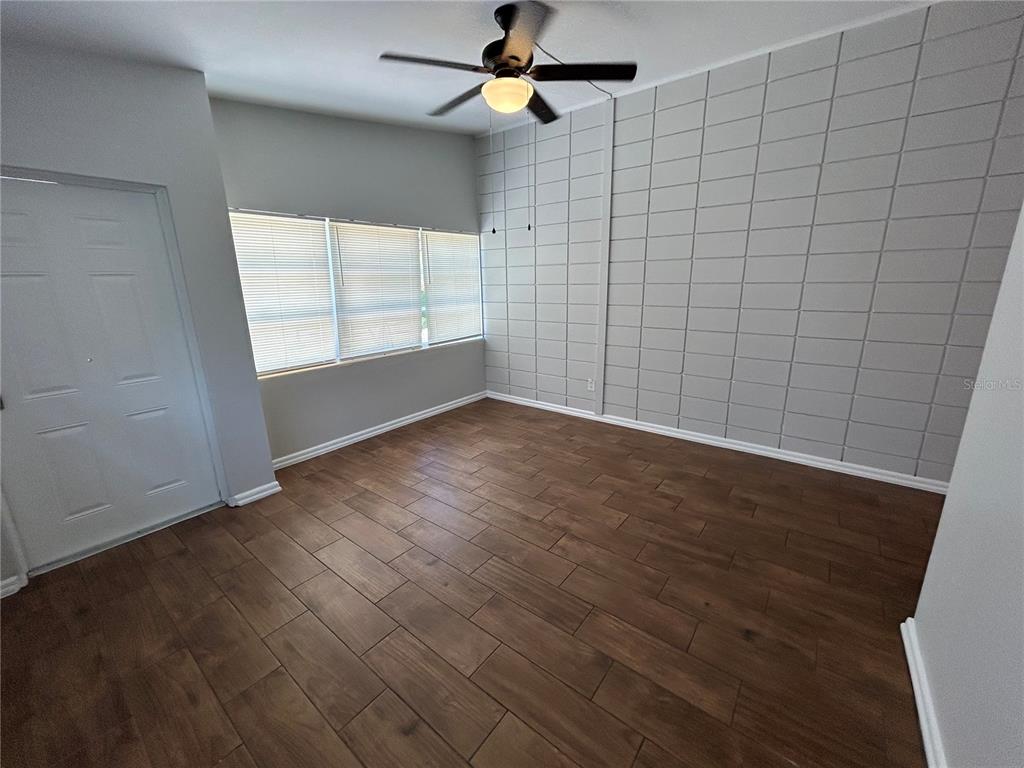An empty room features wood-look tile flooring, a ceiling fan, and a grid-patterned accent wall — 1720 MILLER AVENUE, WINTER PARK, FL