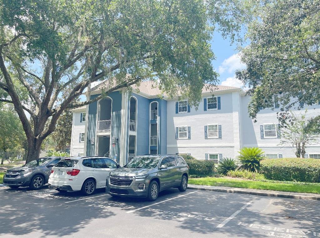 A three-story apartment building with blue accents and parked cars in front — 8203 OLYMPIA COURT, LONGWOOD, FL