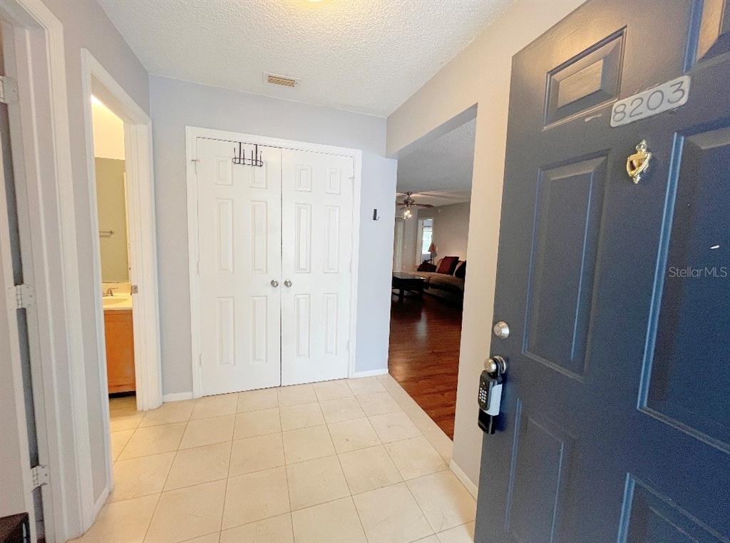 An entryway with tiled floors, a dark blue front door, and white double closet doors — 8203 OLYMPIA COURT, LONGWOOD, FL