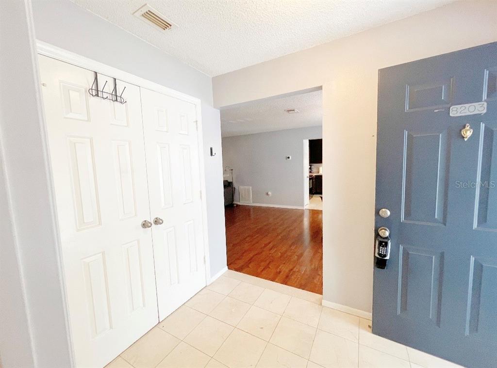 An entryway with tile flooring, a white closet, and a blue front door — 8203 OLYMPIA COURT, LONGWOOD, FL