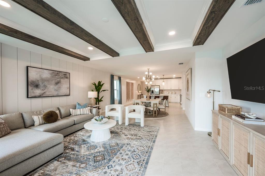 A living room with wood ceiling beams, a sectional sofa, and an open-concept kitchen — 9505 VIBRANT LANE, VENICE, FL
