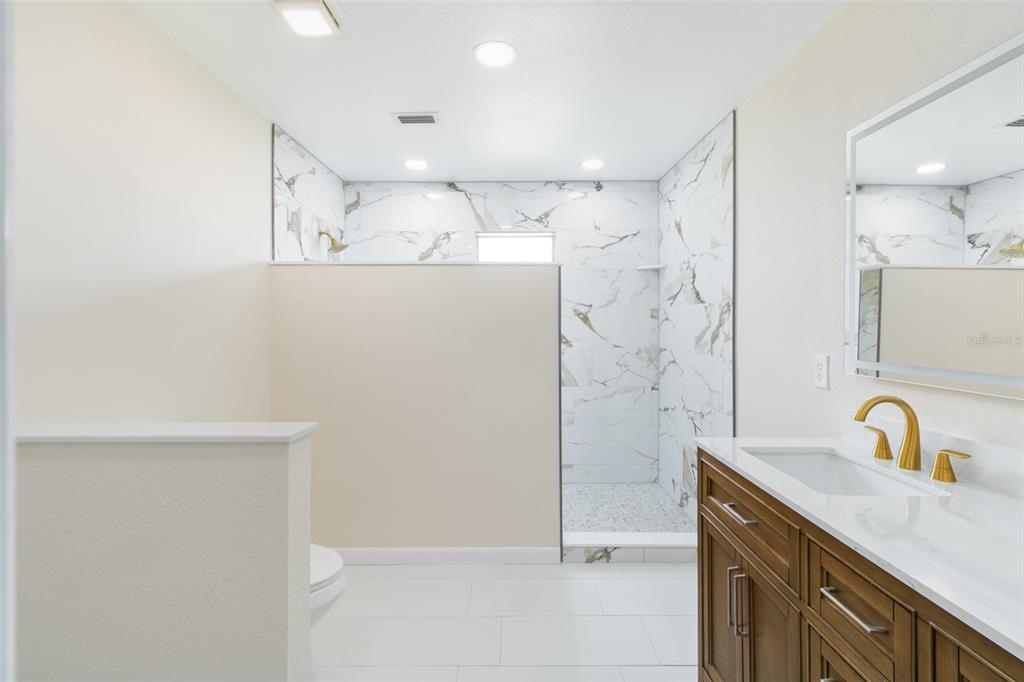 A room with wood-look tile flooring, a ceiling fan, and vertical blinds over a sliding door — 3215 LAKE SAXON DRIVE, LAND O LAKES, FL