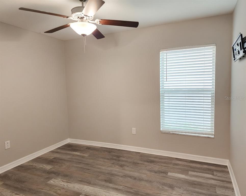 An empty bedroom features gray walls, wood-look flooring, a ceiling fan, and white closet doors — 838 OLIVE CONCH STREET, RUSKIN, FL