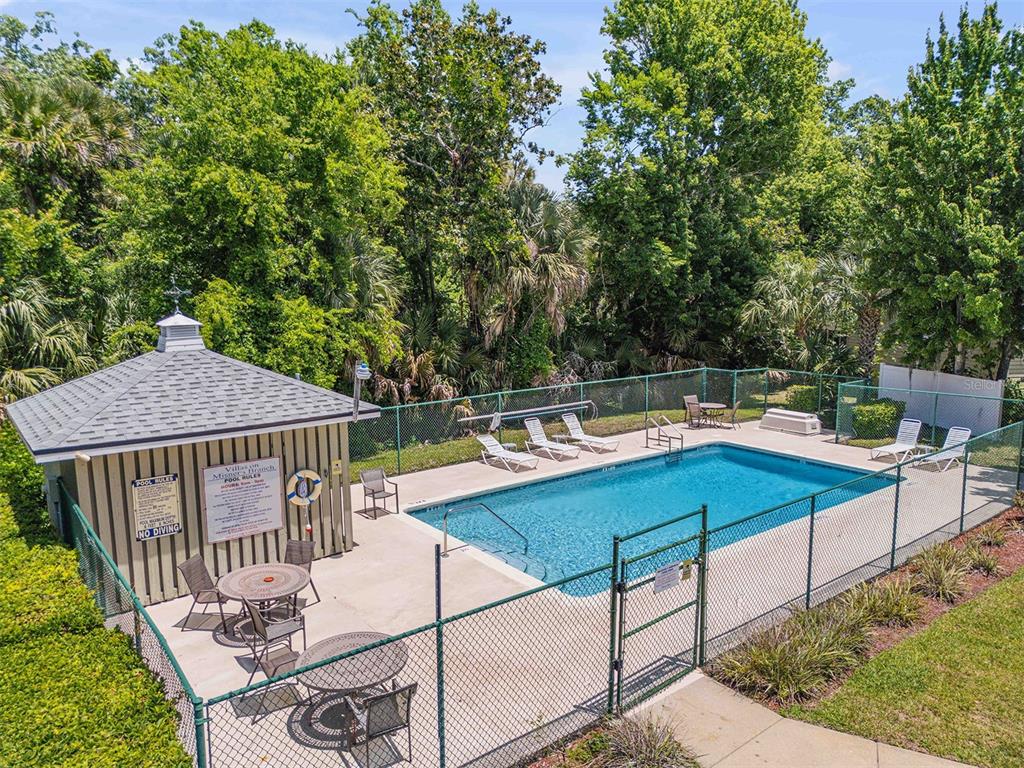 An outdoor swimming pool is enclosed by a chain-link fence next to a small building — 24 MISNERS TRAIL, ORMOND BEACH, FL
