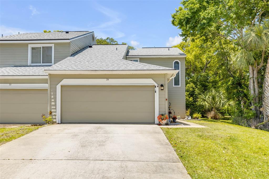 A two-story townhouse exterior features a beige garage, gray siding, and a concrete driveway — 24 MISNERS TRAIL, ORMOND BEACH, FL