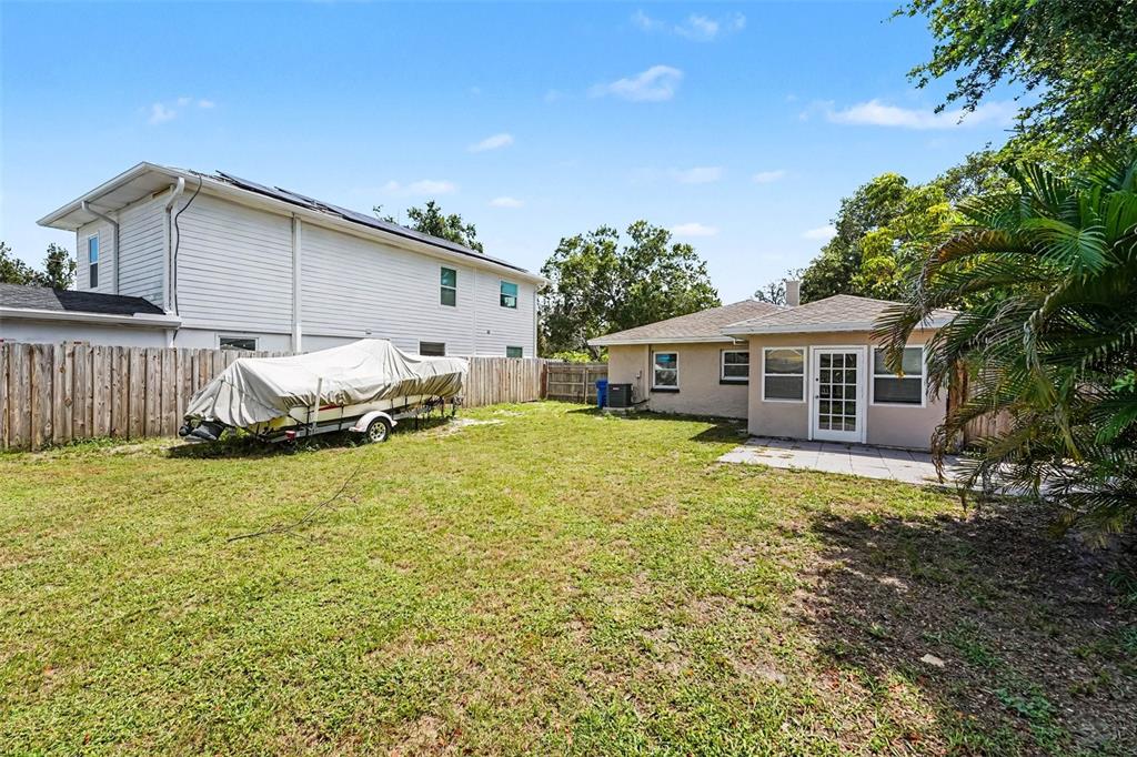 A living room with gray wood-look tile floors, wicker furniture, and an arched kitchen entrance — 4611 17TH AVENUE N, ST PETERSBURG, FL