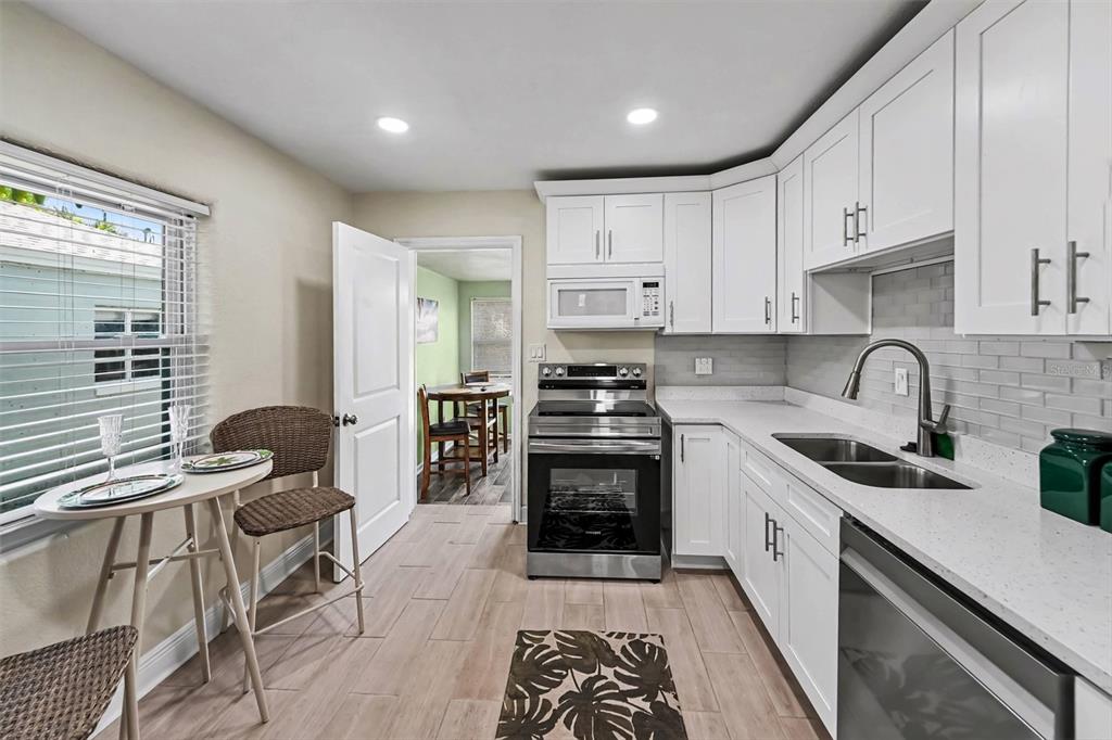 A bedroom with a bed, bench, floor mirror, armchair, and two windows with blinds — 4611 17TH AVENUE N, ST PETERSBURG, FL