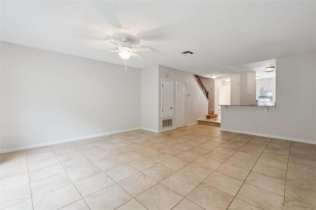 An open living area features light-colored tile flooring, a ceiling fan, and a staircase — 679 CLEMSON DRIVE, ALTAMONTE SPRINGS, FL