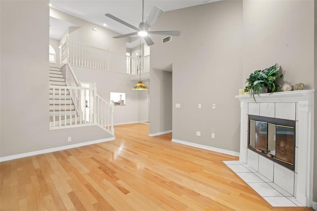 A living room features hardwood floors, a fireplace, a staircase, and a high ceiling — 1937 NORTHFORK CIRCLE, CLEARWATER, FL