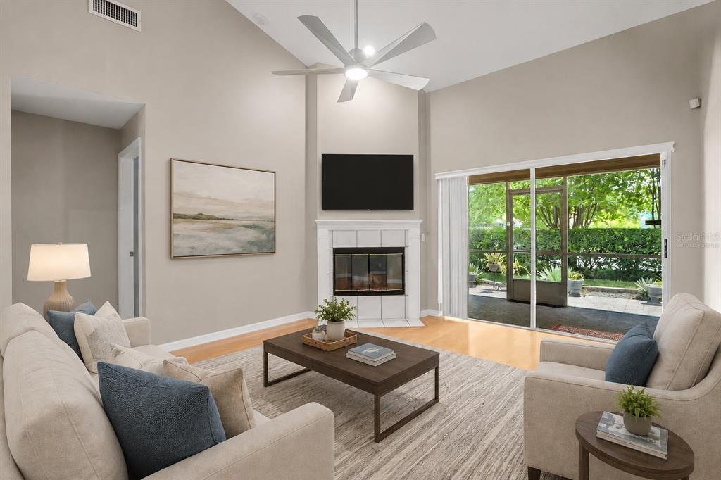 A living room features a fireplace, a mounted television, a ceiling fan, and sliding glass doors — 1937 NORTHFORK CIRCLE, CLEARWATER, FL