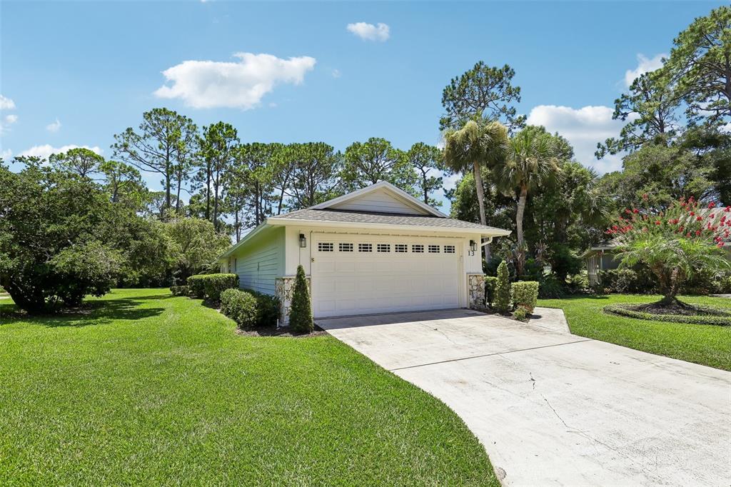 A single-story house with a white garage door and stone accents sits on a grassy lot — 13 JASMINE RUN, ORMOND BEACH, FL