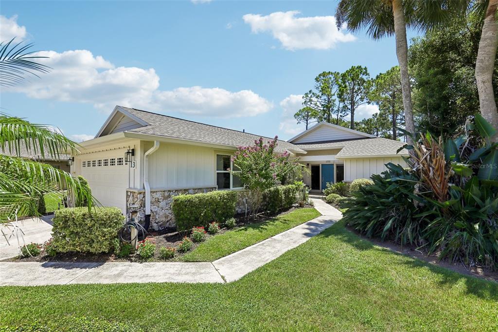 A single-story house with a white garage, stone accents, and a walkway leading to the entrance — 13 JASMINE RUN, ORMOND BEACH, FL