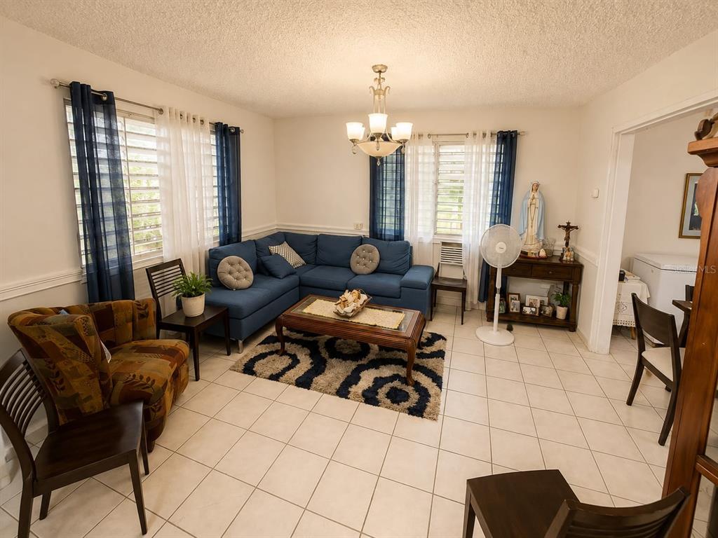 A living room features a blue sectional sofa, a patterned area rug, and tile flooring — 2.2 677 ROAD, VEGA ALTA, PR