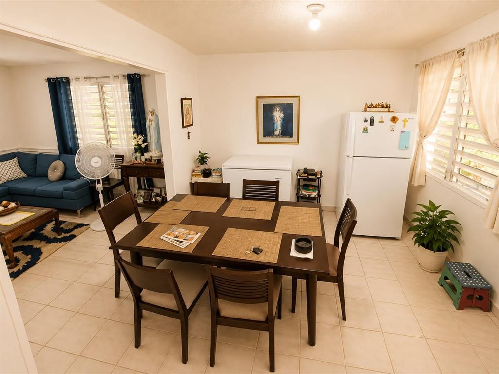 A dining area with a dark wood table and chairs sits adjacent to a living room — 2.2 677 ROAD, VEGA ALTA, PR
