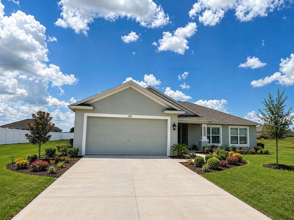A single-story house with a light green exterior, a two-car garage, and a concrete driveway — 1116 CALOOSA RIDGE WAY, BABSON PARK, FL