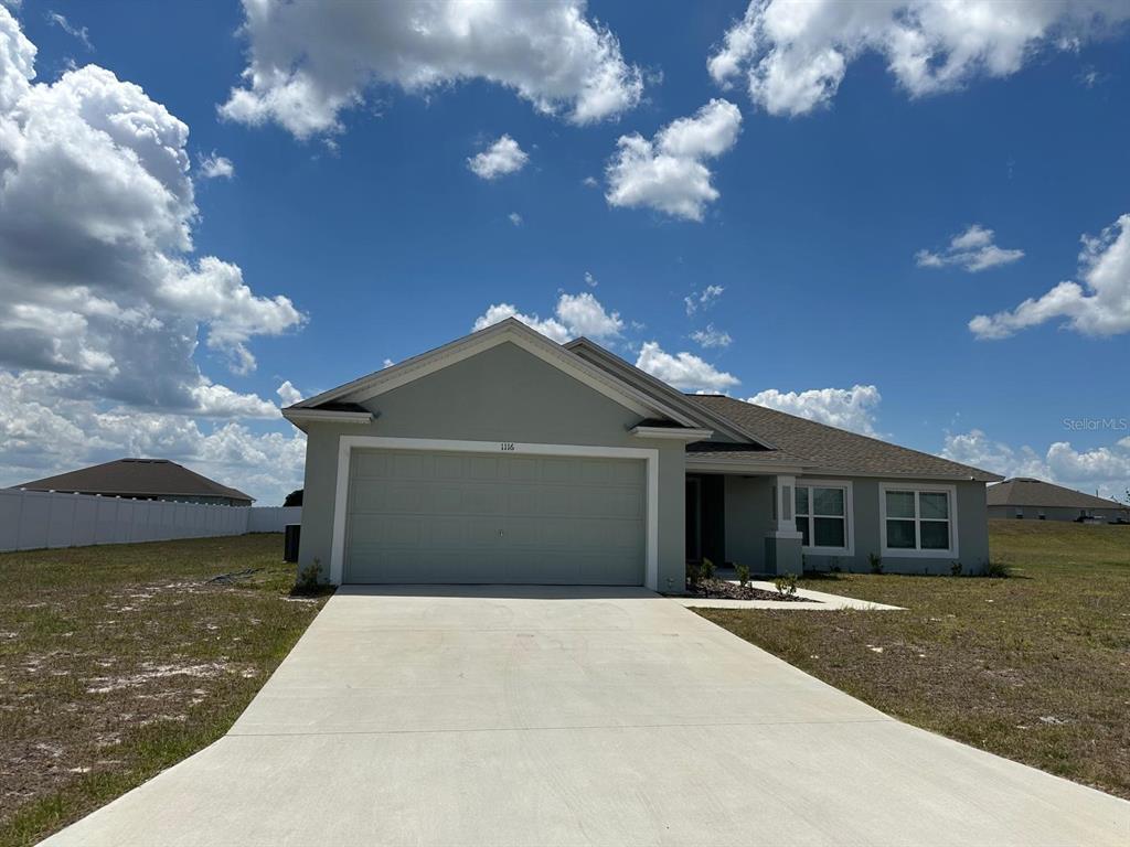 The exterior of a light green house features a blue front door and white trim — 1116 CALOOSA RIDGE WAY, BABSON PARK, FL