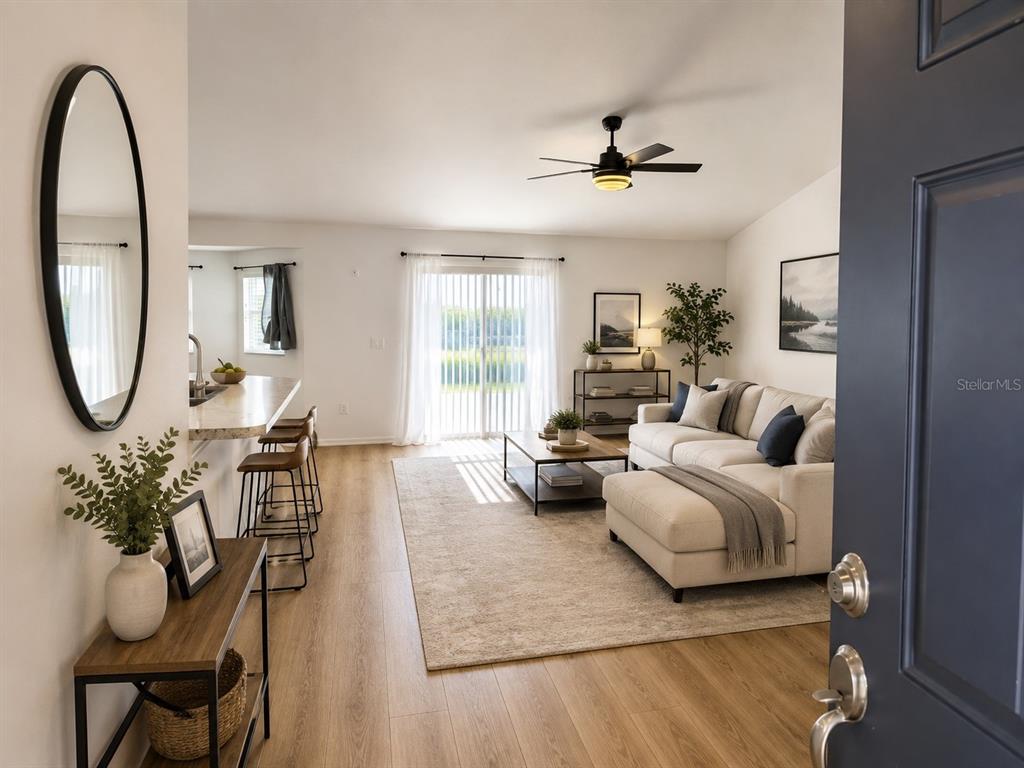 An interior view shows a carpeted living room with a ceiling fan and sliding glass doors — 1116 CALOOSA RIDGE WAY, BABSON PARK, FL
