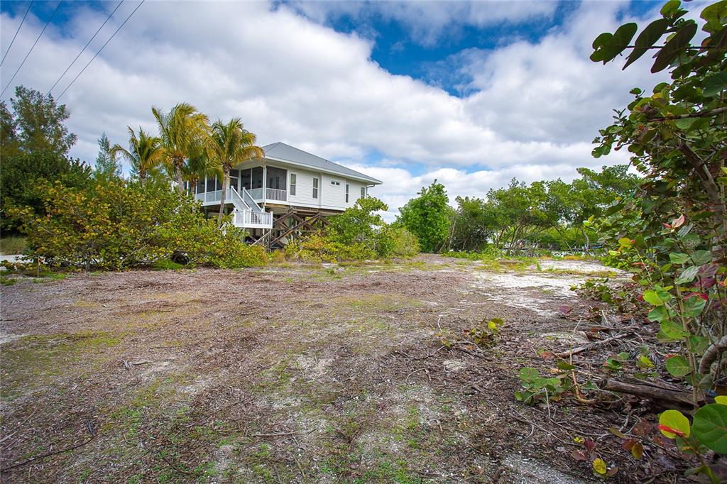 A stilt house sits on a sandy, partially cleared lot surrounded by trees and palms — 270 S GULF BOULEVARD, PLACIDA, FL