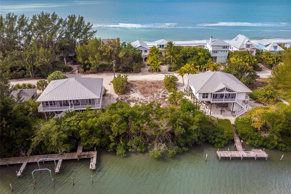 An aerial view shows two elevated coastal houses with private docks on a waterfront lot — 270 S GULF BOULEVARD, PLACIDA, FL