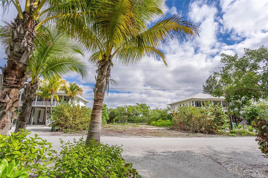 A vacant lot sits between two elevated houses under a cloudy blue sky — 270 S GULF BOULEVARD, PLACIDA, FL