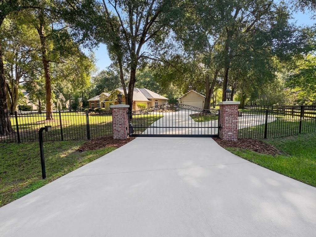 A concrete driveway leads to a gated entrance with brick pillars and a metal fence — 20273 NW 251ST TERRACE, HIGH SPRINGS, FL