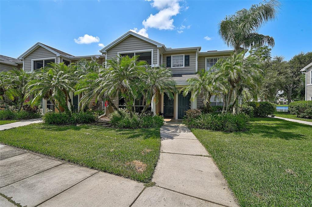 A two-story townhouse exterior with tan siding, palm trees, and a concrete walkway — 8827 MANOR LOOP UNIT 204, LAKEWOOD RANCH, FL