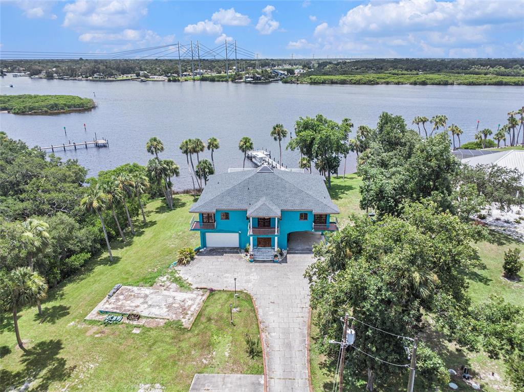 An aerial view shows a bright blue house with a gray roof near a river — 7715 RIVERVIEW DRIVE, RIVERVIEW, FL