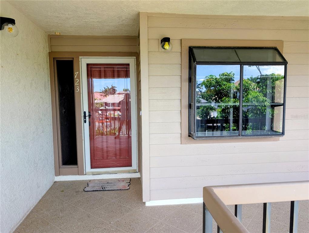 A front porch features a glass storm door, a bay window, and light-colored siding — 3850 MARINERS WALK UNIT 723, CORTEZ, FL