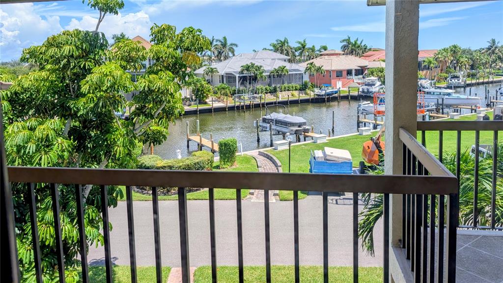 A balcony view overlooks a canal with several boats docked behind residential houses — 3850 MARINERS WALK UNIT 723, CORTEZ, FL