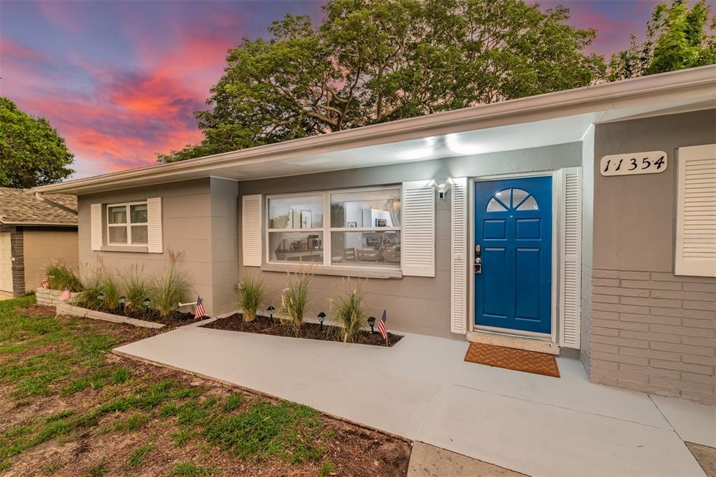 A single-story house with gray siding, a blue front door, and a small front porch — 11354 123RD TERRACE N, LARGO, FL