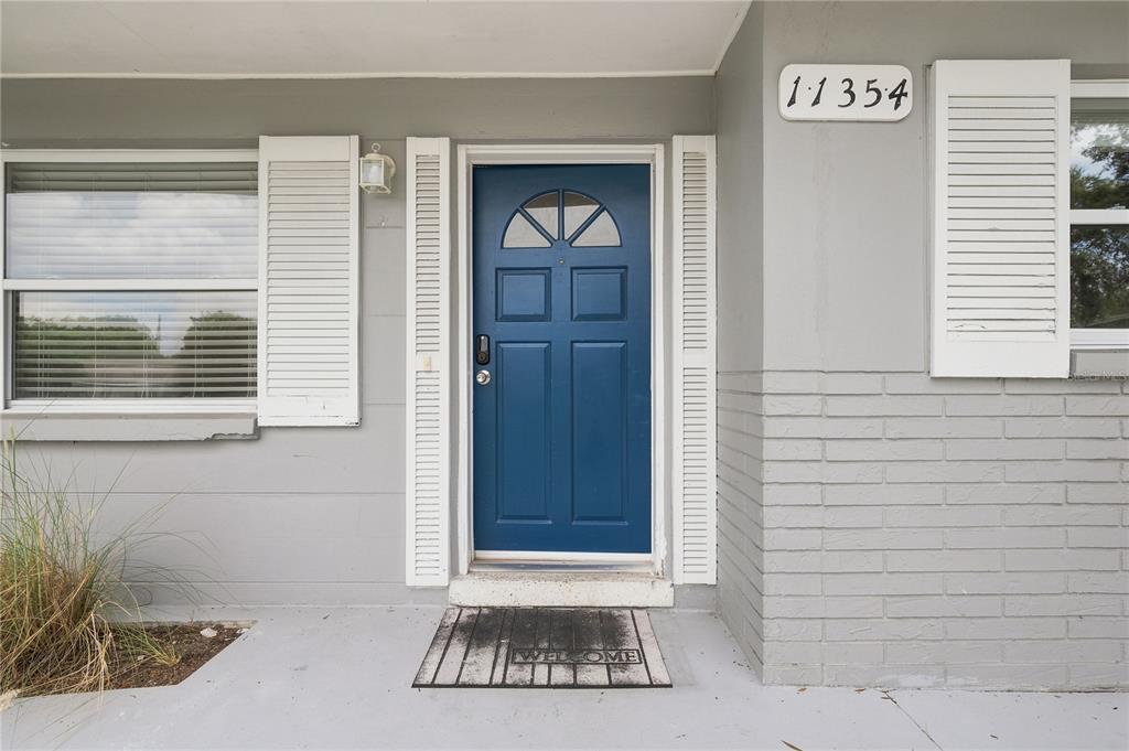 A front entrance features a blue door with a window, white shutters, and a welcome mat — 11354 123RD TERRACE N, LARGO, FL