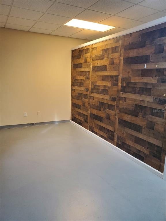 An empty room features a light-colored floor, plain walls, and a wood-paneled accent wall — 1362 US HIGHWAY 1 N, ORMOND BEACH, FL