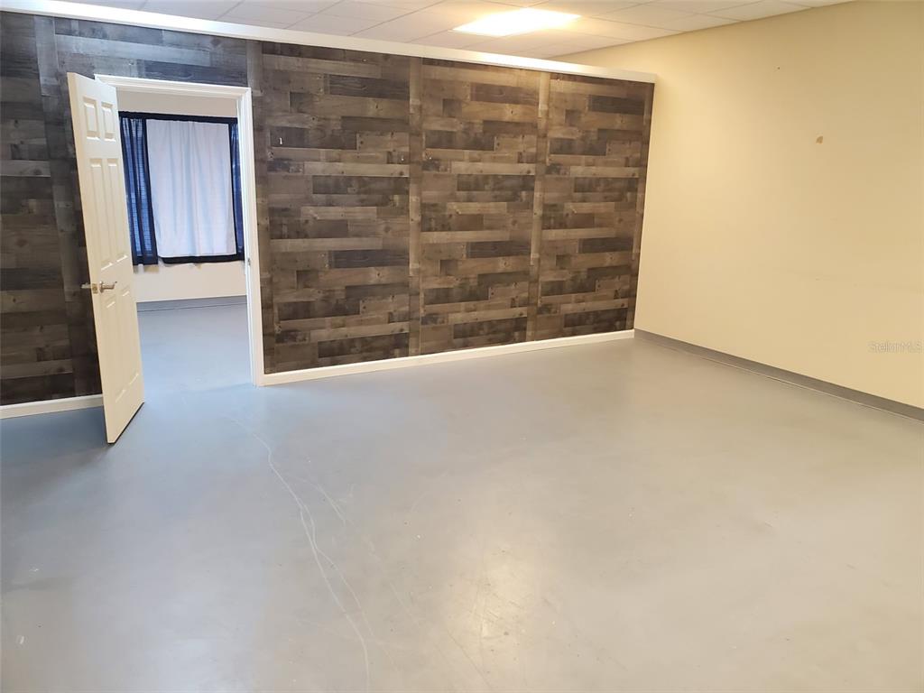A room with gray flooring and a wood-paneled accent wall featuring an open doorway — 1362 US HIGHWAY 1 N, ORMOND BEACH, FL