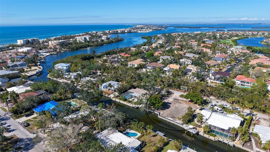 An aerial view shows a vacant waterfront lot circled among residential homes near the coast — 660 LONGVIEW DRIVE, LONGBOAT KEY, FL