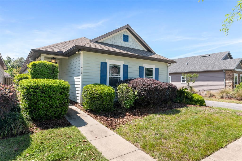 A single-story house with light green siding, blue shutters, and a front walkway — 7916 SW 80TH DRIVE, GAINESVILLE, FL