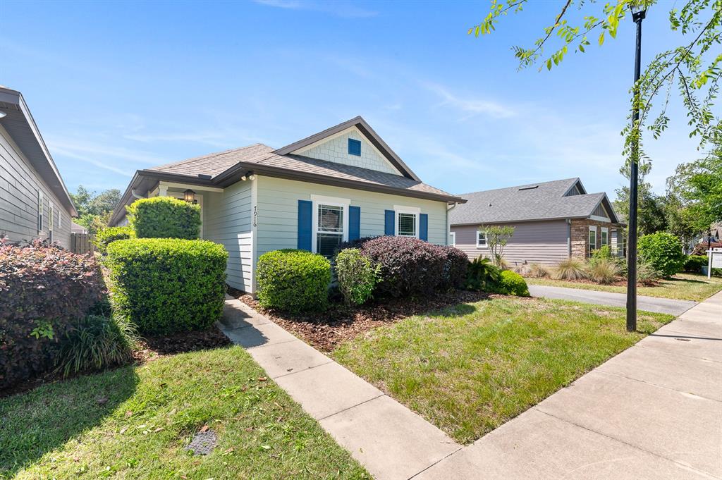A light green single-story house with blue shutters and a front walkway on a sunny day — 7916 SW 80TH DRIVE, GAINESVILLE, FL