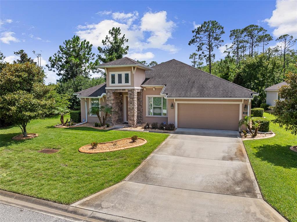 A single-story house with a stone-accented entryway, a two-car garage, and a landscaped front yard — 685 ALDENHAM LANE, ORMOND BEACH, FL