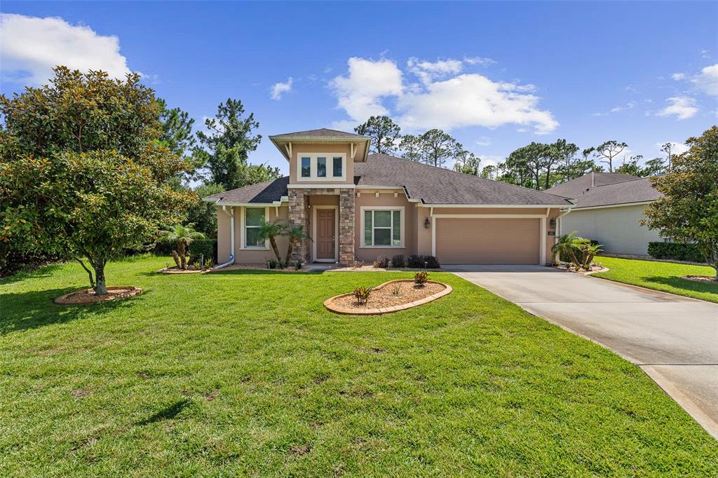 A single-story house with a stone-accented entryway, a two-car garage, and a manicured lawn — 685 ALDENHAM LANE, ORMOND BEACH, FL