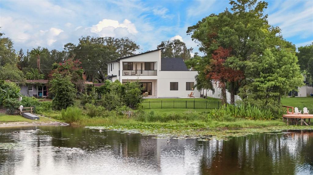 A modern two-story house features a wood-paneled facade, white stone garage, and a slanted roof — 1205 FALCON DRIVE, ORLANDO, FL