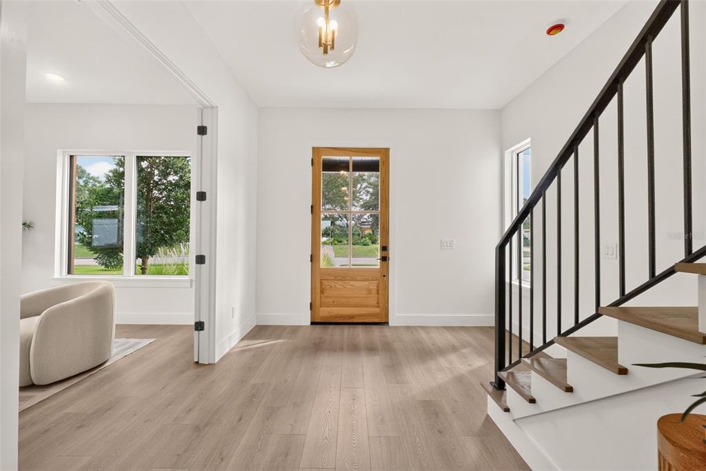 A modern home entrance features horizontal wood siding, a glass-paneled door, and two black sconces — 1205 FALCON DRIVE, ORLANDO, FL