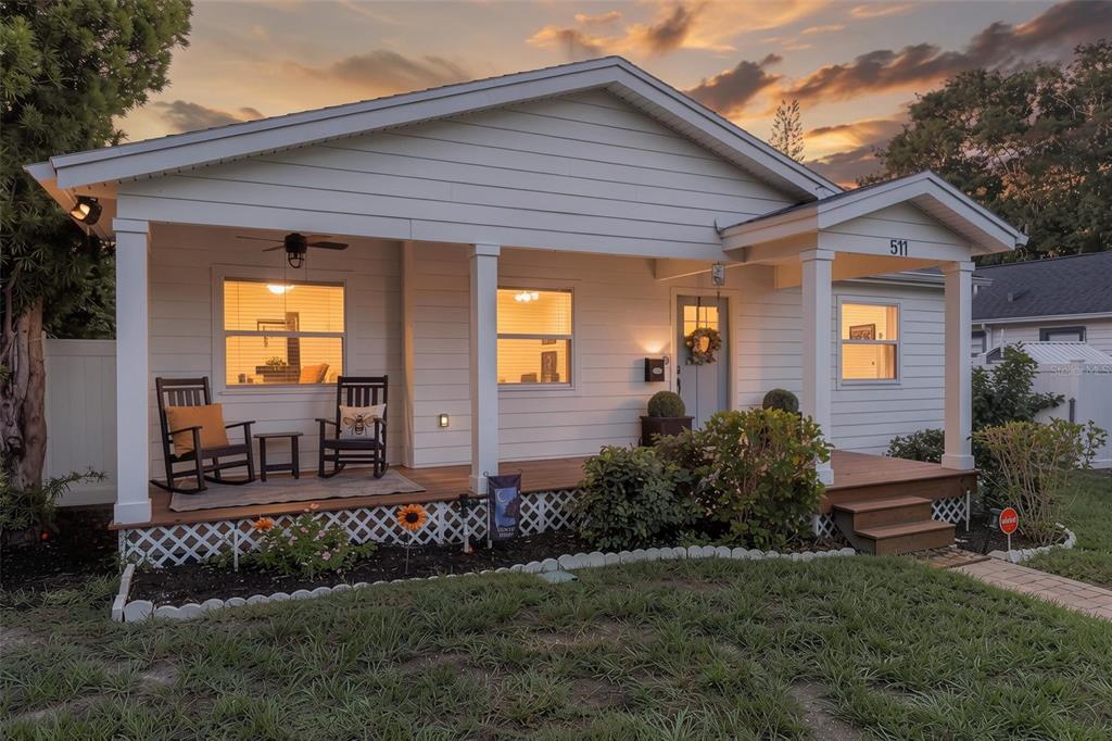 A white house with a covered front porch, rocking chairs, and a wooden deck — 511 25TH AVENUE N, ST PETERSBURG, FL