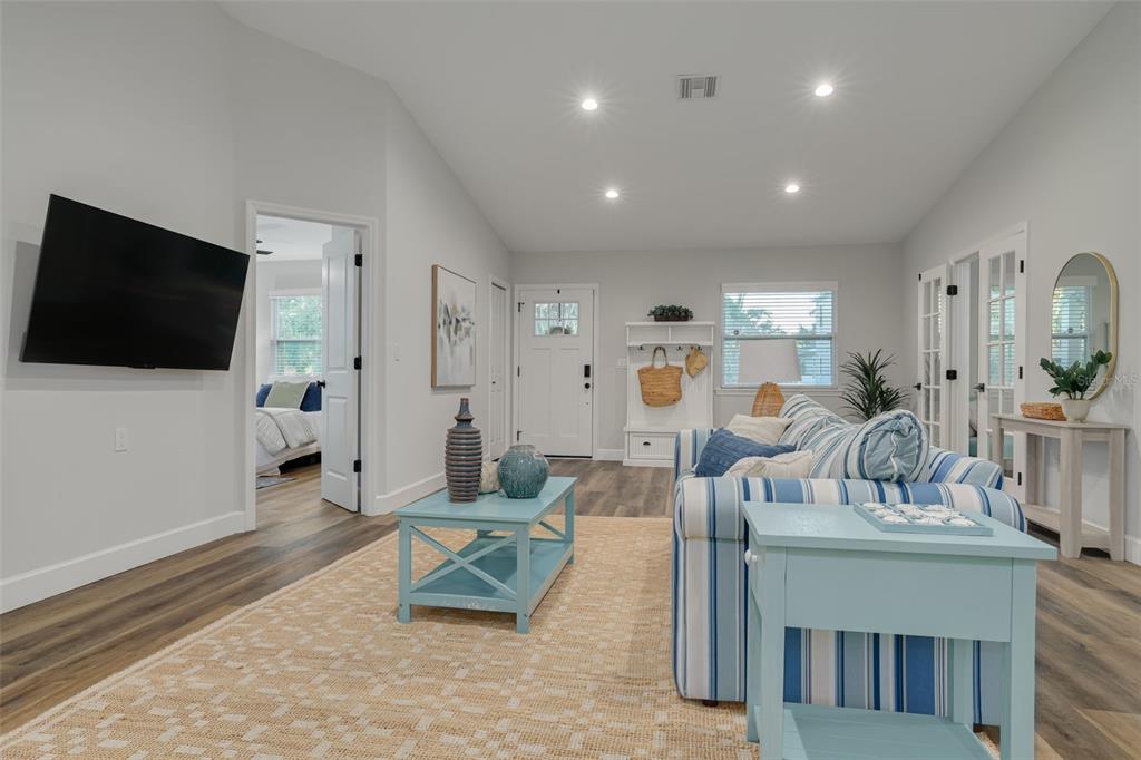 A living room features a striped sofa, light blue furniture, and wood-look flooring — 511 25TH AVENUE N, ST PETERSBURG, FL