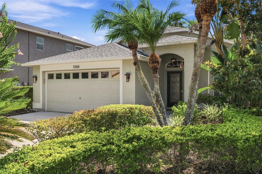 A single-story house with a beige stucco exterior, a two-car garage, and palm trees — 13108 ROYAL GEORGE AVE, ODESSA, FL
