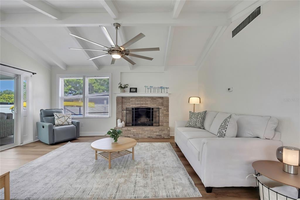 A living room features a brick fireplace, white sofa, gray armchair, and a ceiling fan — 6080 WAVERLY ROAD, WEEKI WACHEE, FL