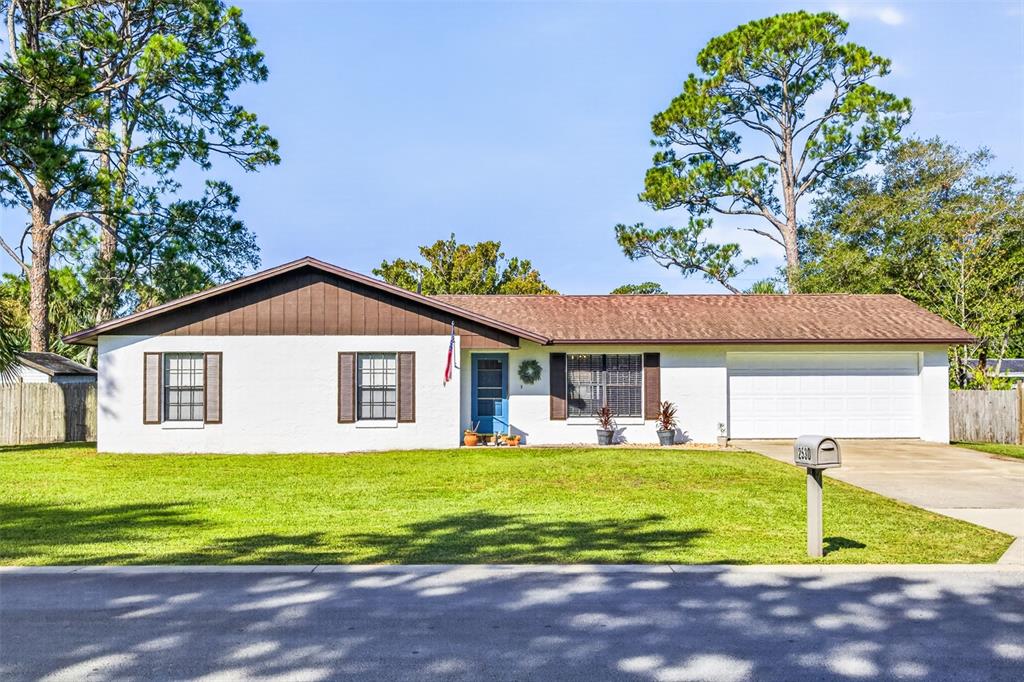 A single-story white house with brown shutters, a blue front door, and a two-car garage — 2530 NORDMAN AVENUE, NEW SMYRNA BEACH, FL